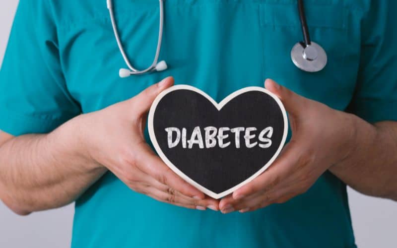 Image of a vet holding a black heart shaped ornament with the word diabetes written in the centre