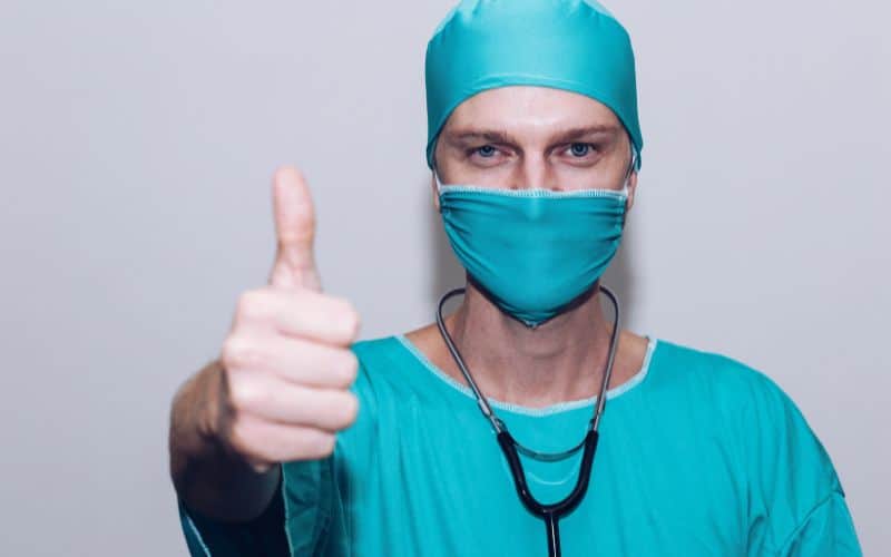 Image of a happy surgeon in their scrubs, giving a thumbs up