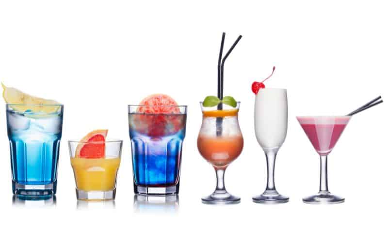 Different sized and shaped glasses containing different colored alcoholic drinks